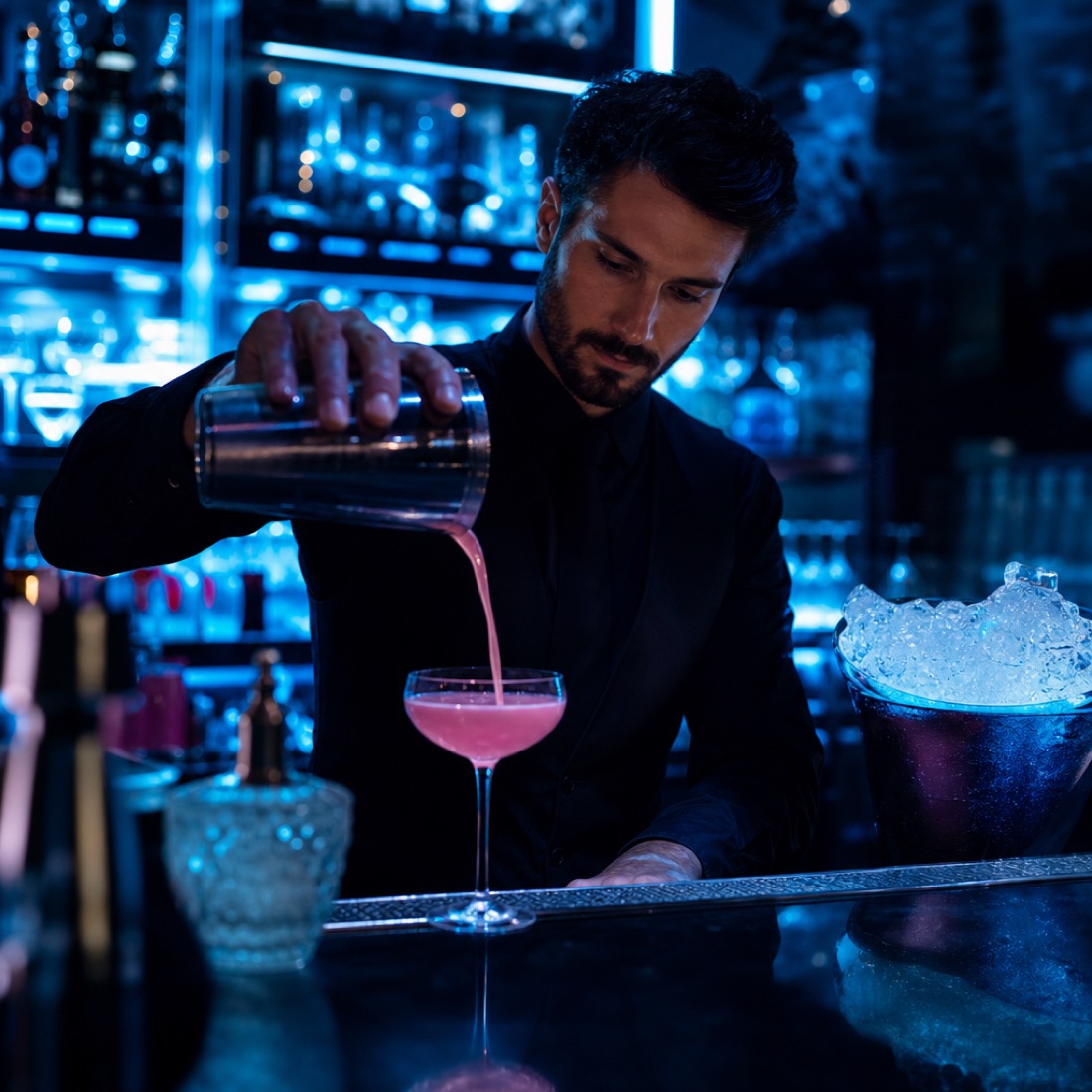 Bartender pouring a cocktail at the backlit bar at New Ice